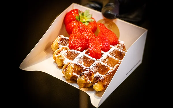 Een warme wafel met poedersuiker en verse aarbeien